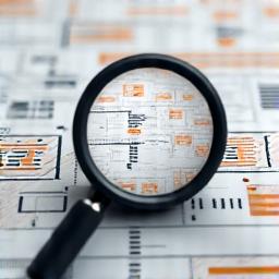 A magnifying glass examining a complex flowchart.